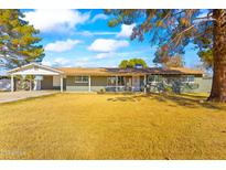 Charming single-story home featuring a large front yard with mature trees and a covered carport at 11446 W Hidalgo Ave, Tolleson, AZ 85353