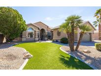 Beautiful single-story home with desert landscaping, artificial turf, palm trees, and neutral exterior paint at 15385 W Indianola Ave, Goodyear, AZ 85395