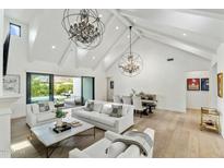 Bright living room featuring vaulted ceilings, modern chandeliers, and seamless indoor/outdoor flow to the pool area at 3808 E Fairmount Ave, Phoenix, AZ 85018