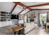 Bright living room boasts vaulted ceilings, wooden beams, brick fireplace, and built-in shelving at 3923 S Dorsey Ln, Tempe, AZ 85282