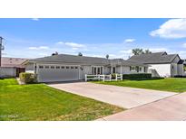 Charming single-story home with a gray exterior, lush green lawn, and a driveway leading to an attached two-car garage at 4239 E Mitchell Dr, Phoenix, AZ 85018