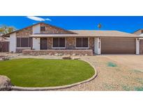 Charming stone-accented home with a manicured lawn and a two-car garage, nestled under a clear blue sky at 17408 N 14Th Ave, Phoenix, AZ 85023