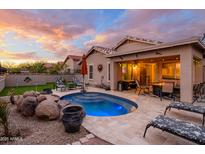 Inviting backyard oasis featuring a custom pool, travertine patio, and covered outdoor living area with sunset views at 23175 W Arrow Dr, Buckeye, AZ 85326