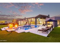 Resort-style backyard with luxurious pool, lounge chairs, fire pit, and lush green lawn at 29501 N 76Th St, Scottsdale, AZ 85266