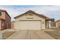 Beige single-story home featuring a two-car garage, low maintenance desert landscaping, and a brown roof at 7410 W Eva St, Peoria, AZ 85345