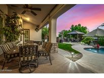 Covered outdoor patio with dining area, stone columns, and views of the pool and landscaped backyard at 11336 N 117Th Way, Scottsdale, AZ 85259