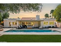 Inviting pool area with modern outdoor seating and a covered patio, perfect for relaxation and entertaining at sunset at 10524 E Cannon Dr, Scottsdale, AZ 85258