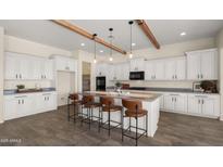 Bright kitchen features white cabinets, wood beams, stainless steel appliances, and a large center island with bar seating at 22318 S 226Th Pl, Queen Creek, AZ 85142