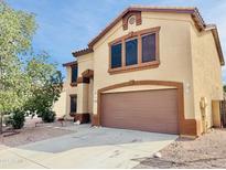 Two-story home featuring a two-car garage, low maintenance landscaping, and desert surroundings under a bright blue sky at 10563 E Bramble Ave, Mesa, AZ 85208