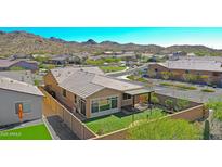 Stunning backyard features lush green synthetic grass, a brick fence, covered patio and mountain views at 16788 W Beth Dr, Goodyear, AZ 85338