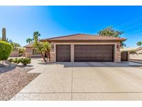 Attached two-car garage with stone accents, a clay tile roof, and wide driveway at 2890 N 156Th Dr, Goodyear, AZ 85395