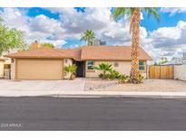 Charming single-story home featuring a desert landscape, mature palm trees, and a two-car garage at 6248 W Hearn Rd, Glendale, AZ 85306