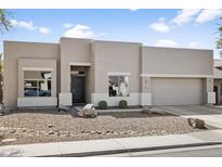 Contemporary single-story home featuring neutral stucco, rock landscaping, and a two-car garage, with a black front door at 10721 E Pampa Ave, Mesa, AZ 85212