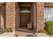 Inviting front entrance with custom stone accents, a decorative wood door, and lush landscaping at 1668 E Saltsage Dr, Phoenix, AZ 85048