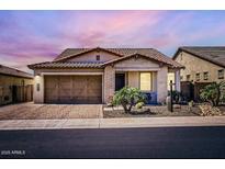 Charming single-story home with a two-car garage, desert landscaping, and a tiled roof under a beautiful sunset sky at 26978 N 74Th Ln, Peoria, AZ 85383