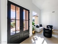 Bright entryway with double glass doors leading into a modern living room with white walls and elegant furniture at 9238 E Palm Tree Dr, Scottsdale, AZ 85255