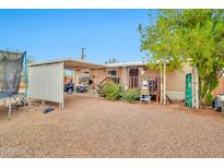 Spacious home backyard featuring a covered patio, gravel ground cover and mature trees at 520 N Ocotillo Dr, Apache Junction, AZ 85120