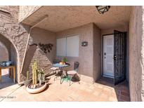 Inviting front porch with red tile, stylish metal lizards, and a cozy table and chairs for outdoor enjoyment at 7312 N Via Camello Del Norte St # 95, Scottsdale, AZ 85258