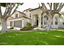 Inviting home featuring a charming front yard, lush green lawn, and a two-car garage perfect for families at 1450 N Sailors Way, Gilbert, AZ 85234