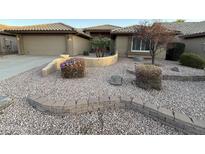 Charming desert-landscaped front yard with decorative rocks, flowering bushes, and a curved retaining wall at 8541 W Rosemonte Dr, Peoria, AZ 85382