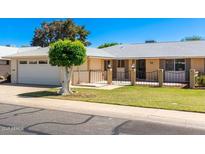 Charming single story home with well-manicured lawn, mature landscaping, and an attached two car garage at 10839 W Peoria Ave, Sun City, AZ 85351