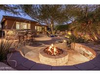 Inviting backyard with a stone fire pit, mature trees, and outdoor seating, perfect for entertaining at 11496 E Pine Valley Rd, Scottsdale, AZ 85255