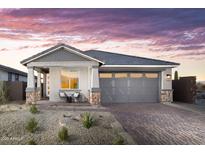 Charming home with a gray color scheme, desert landscaping, and brick driveway at 17216 W Sunward Dr, Goodyear, AZ 85338