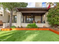 Inviting covered back patio with lush landscaping and comfortable outdoor seating overlooking a well-manicured artificial lawn at 2537 N Miller Rd, Scottsdale, AZ 85257