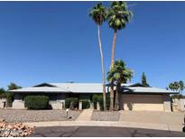 Charming single-story home features mature palm trees, a neutral color palette, and a well-maintained front yard at 4602 W Orchid Ln, Glendale, AZ 85302