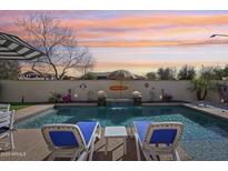 Inviting backyard pool with lounge chairs, tropical accents, and tranquil water features at sunset at 5779 S Penrose Dr, Gilbert, AZ 85298