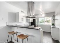 Modern kitchen features white cabinets, stainless steel appliances and a breakfast bar with two stools at 749 E Montebello Ave # 228, Phoenix, AZ 85014