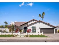 Charming stucco home boasts a tile roof, manicured lawn, flowering bushes, and attached two-car garage at 8654 E Thoroughbred Trl, Scottsdale, AZ 85258