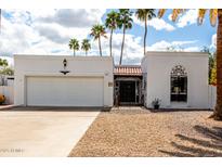 Charming single-story home boasts a pristine white exterior, low maintenance landscaping, and desert palms at 115 E Piping Rock Rd, Phoenix, AZ 85022