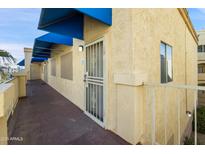 Exterior entrance featuring a security door, blue awning, and textured stucco facade for a secure, stylish welcome at 12221 W Bell Rd # 215, Surprise, AZ 85378