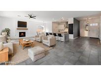 Spacious living room featuring a fireplace, ceiling fan, and an open floor plan leading into the kitchen at 16617 S 16Th Ave, Phoenix, AZ 85045