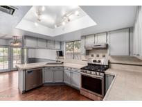 Well lit kitchen features stainless steel appliances, gray cabinets, and a window with a view to the backyard at 730 E Rosemonte Dr, Phoenix, AZ 85024