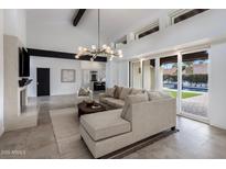 Spacious living area with tiled floors and modern decor flows into adjacent kitchen; view of pool through doors at 9675 E Cinnabar Ave, Scottsdale, AZ 85258