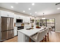 Bright kitchen featuring stainless steel appliances, white cabinets, and a center island with bar seating at 9705 E Mountain View Rd # 1056, Scottsdale, AZ 85258