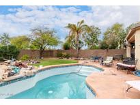 Backyard swimming pool with tiled edges, stone waterfall feature, and patio furniture around pool deck at 13331 W Romain Ct, Litchfield Park, AZ 85340