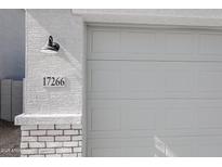 Close-up of the garage door with a house number and exterior light fixture at 17266 W Daley Ln, Surprise, AZ 85387