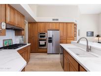 Bright kitchen boasts stainless steel appliances, wooden cabinets and a spacious island with white countertops at 9475 N 115Th Pl, Scottsdale, AZ 85259