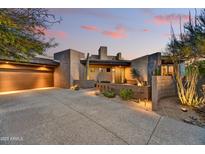 Contemporary home showcasing desert landscaping, a covered garage, and unique architectural design at sunset at 10567 E Fernwood Ln, Scottsdale, AZ 85262