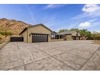 Long shot of an elegant home featuring multiple garages, desert landscaping, and a private gated entrance at 5301 E Paradise Canyon Rd, Paradise Valley, AZ 85253