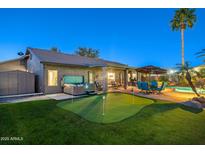 This backyard features a putting green, covered patio, hot tub and a pool, perfect for outdoor entertaining at 20497 E Appaloosa Dr, Queen Creek, AZ 85142