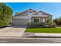 Charming single-story home featuring manicured lawn, gray siding, and an attached two car garage at 2595 E Harrison Ct, Gilbert, AZ 85295