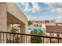 Balcony view of the community pool surrounded by desert landscaping on a partly cloudy day at 5518 E Lindstrom Ln # 2038, Mesa, AZ 85215