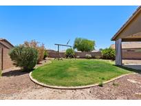 Well-maintained backyard with lush lawn, rock landscaping, and a wooden swing set for outdoor enjoyment at 16653 N 169Th Ave, Surprise, AZ 85388