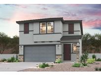 Charming two-story home featuring a gray stucco exterior, stone accents, and well-maintained landscaping at 17229 W Daley Ln, Surprise, AZ 85387