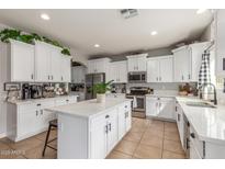 Bright kitchen with white cabinets, stainless steel appliances, an island, and stone countertops at 24805 W Vista Norte St, Buckeye, AZ 85326