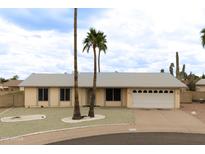 Charming single-story home with palm trees, light yellow exterior and low maintenance desert landscaping at 4227 E Yowy St, Phoenix, AZ 85044